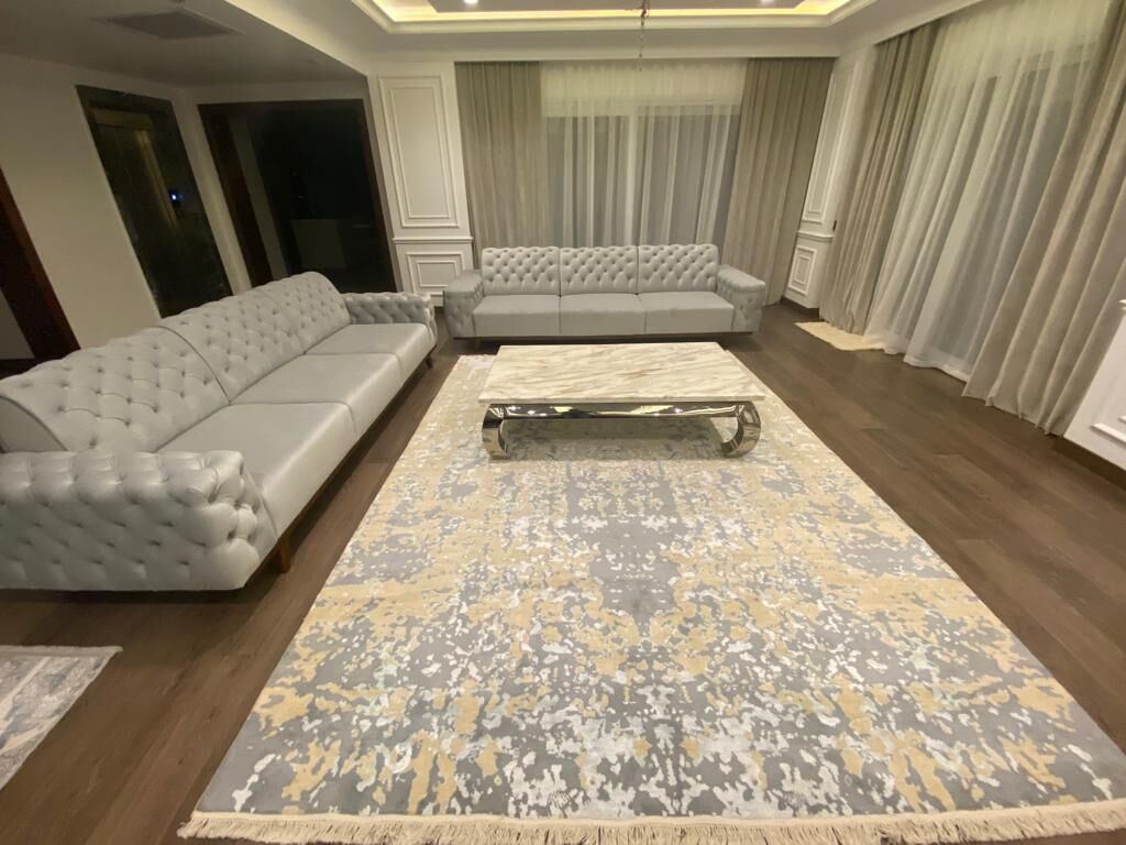 Long tufted white sofa with a stone-topped coffee table on a blue-grey and gold rug