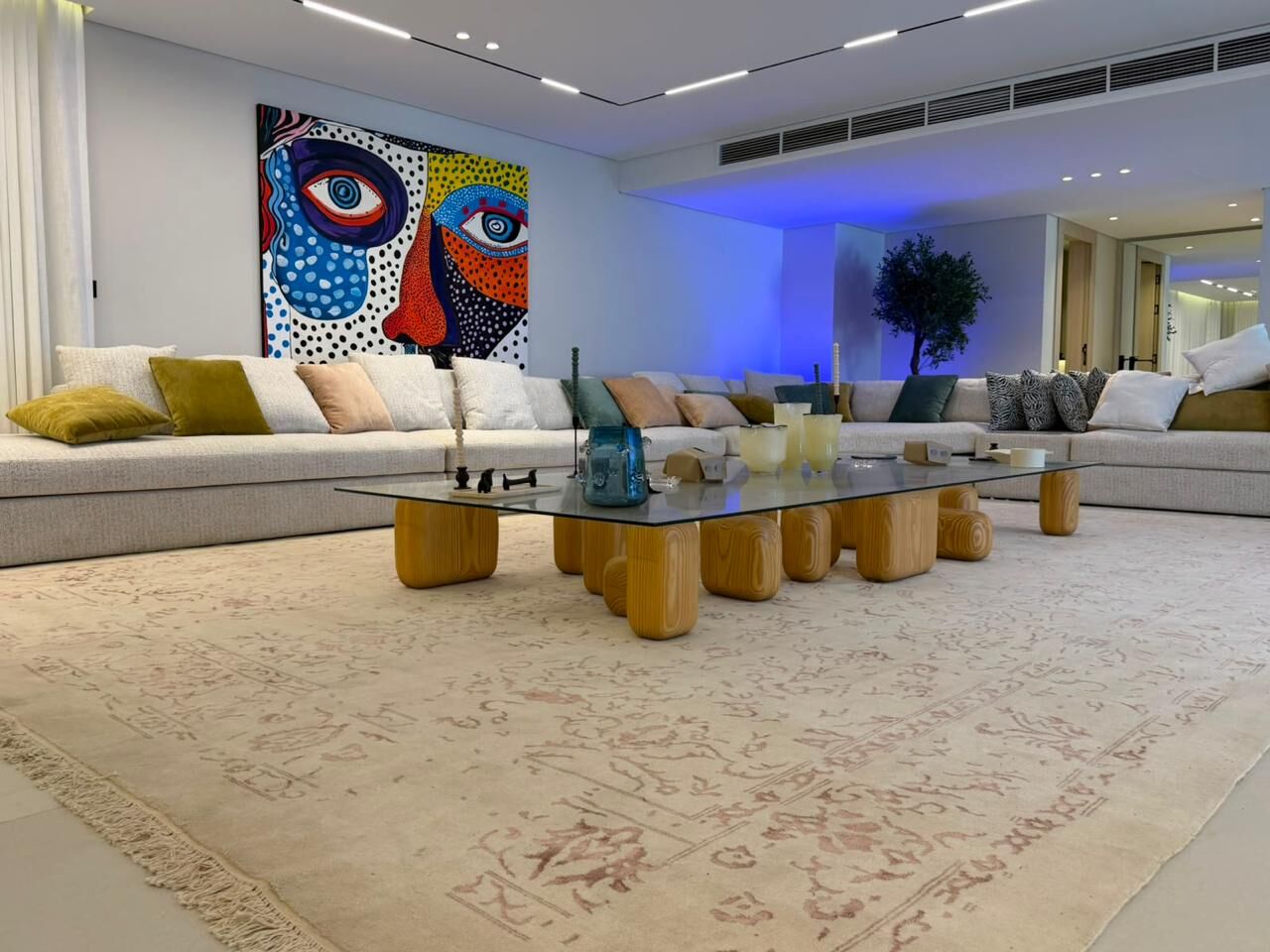 Large living room with a colourful painting and a long sofa, on a pale rug